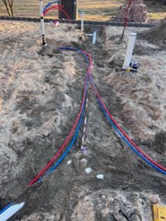 Colored utility cables laid in a dirt trench at a construction site