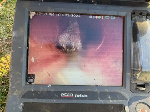 Close-up of a borescope screen showing a pink, blurry pipe or tunnel interior with a dark center hole.