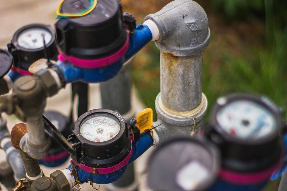 Close-up of water meters and metal pipes with black and blue fittings outdoors
