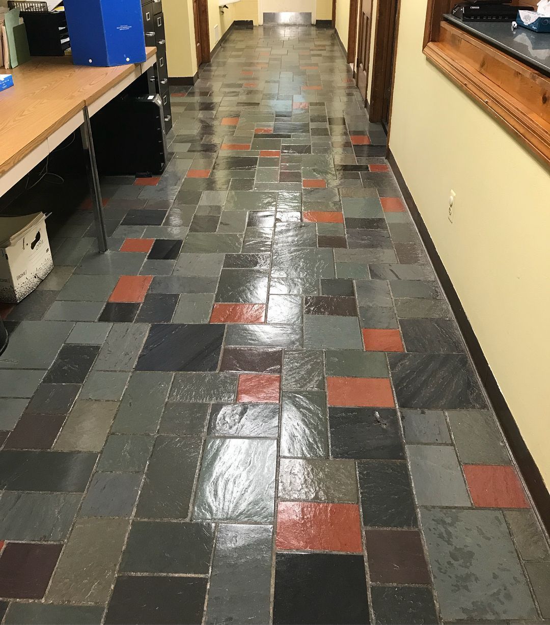Hallway with multi-colored stone tile floor; red, grey, and black tiles. A desk is on one side.