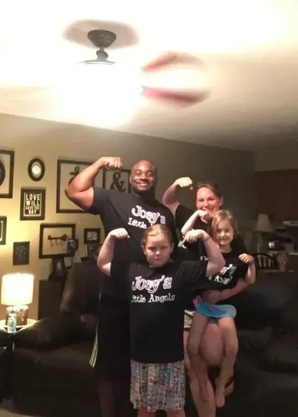 Family flexing biceps, wearing matching black shirts with 