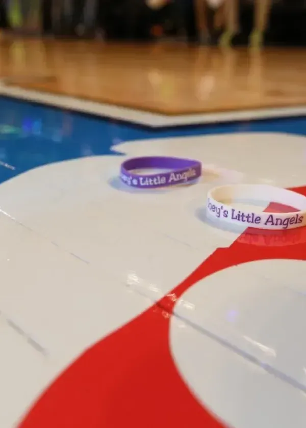 Two wristbands on a painted surface, one purple, one white, with 