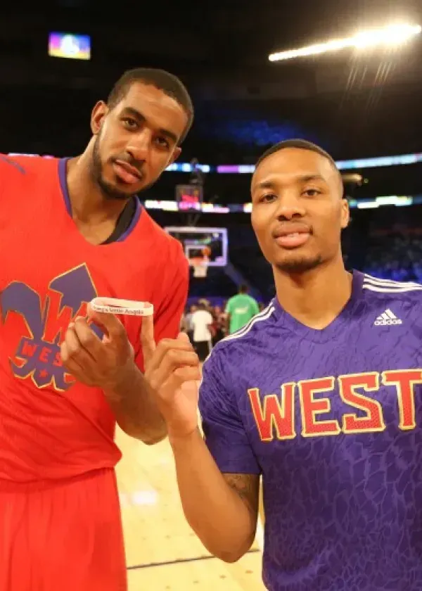Two basketball players in athletic wear, one in red, one in purple, pose together.