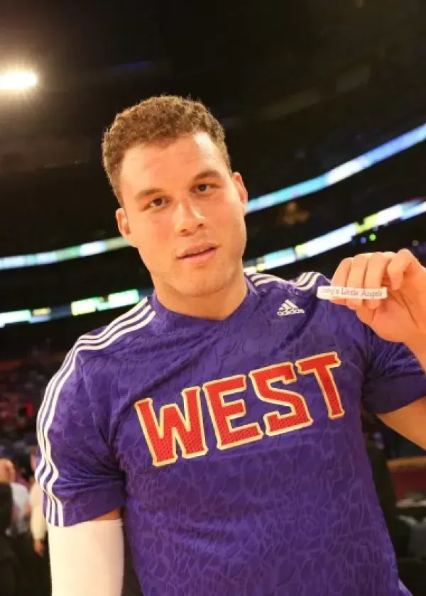Blake Griffin in a purple West All-Star jersey holding a wristband at a basketball game.