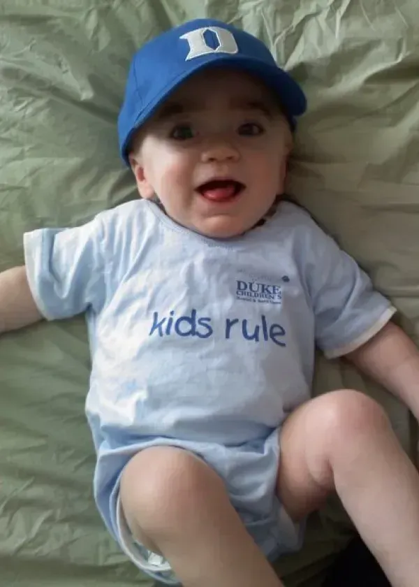 Baby wearing a blue Duke baseball cap and a light blue 