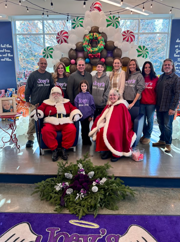 Group photo with Santa and Mrs. Claus, standing in front of a holiday-themed balloon display.