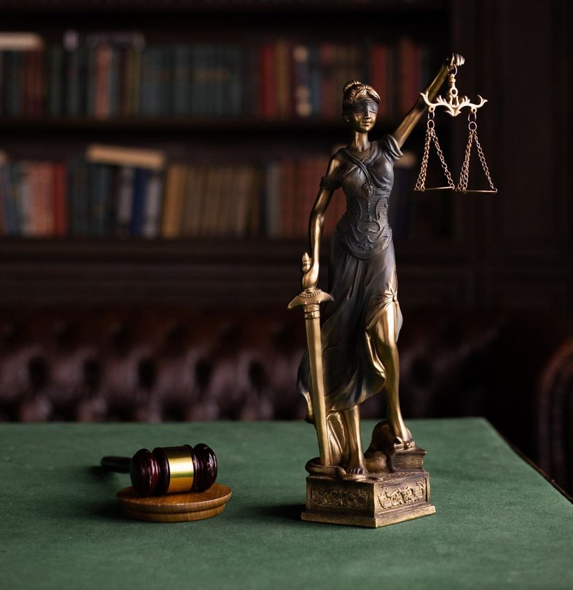 a scale of justice and a judge 's gavel are on a wooden table .