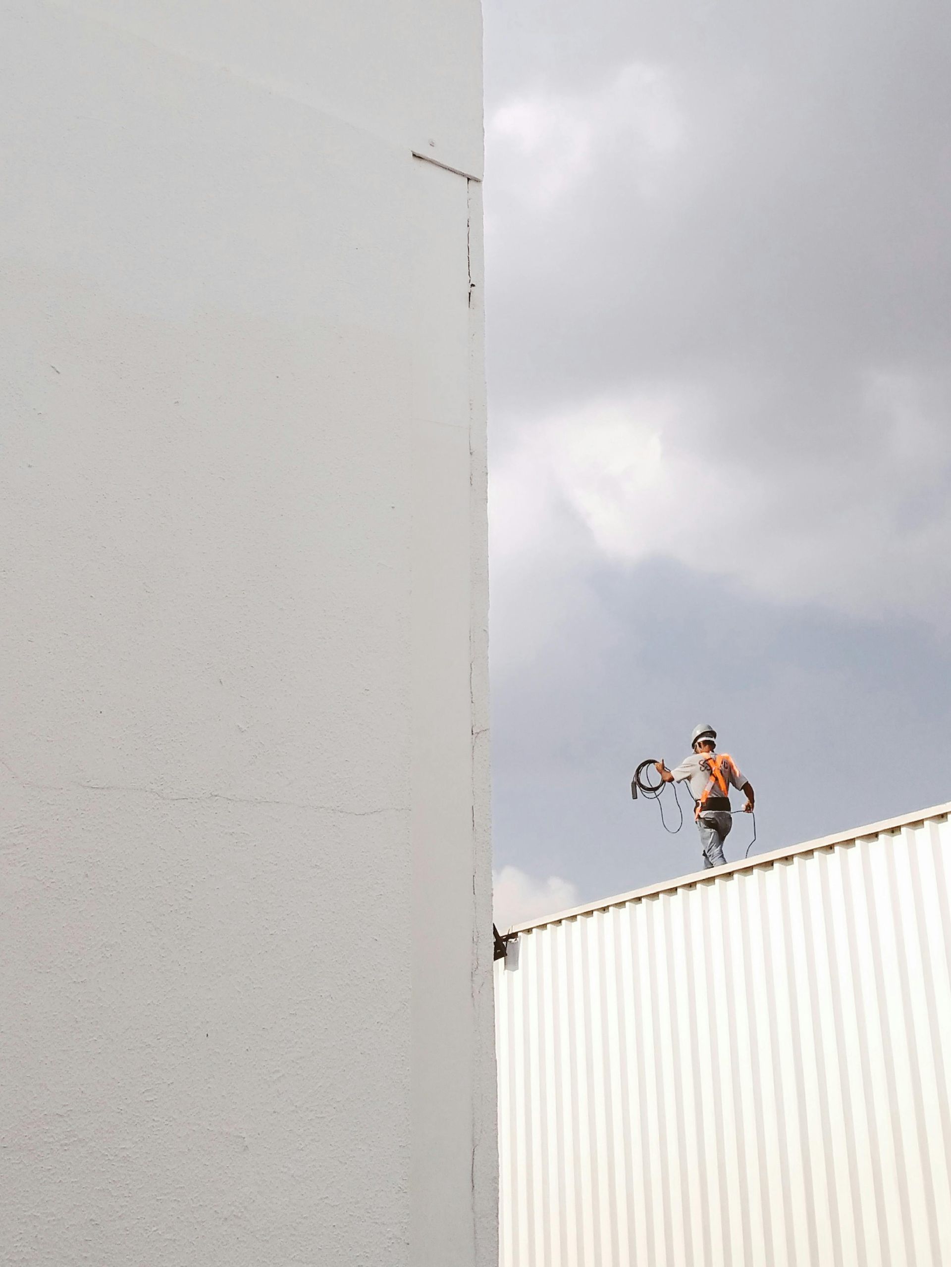 A man is standing on the roof of a building holding a tennis racquet.