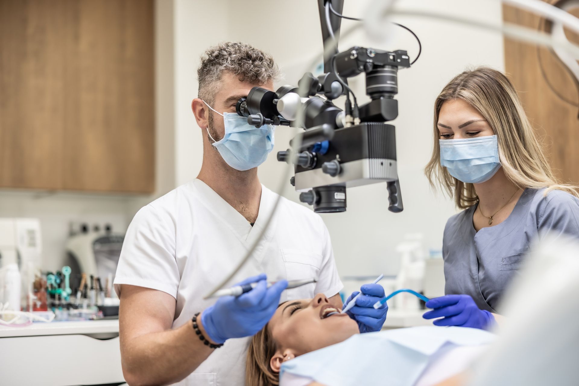 Dentists using a microscope to examine teeth during a local dental implant evaluation.