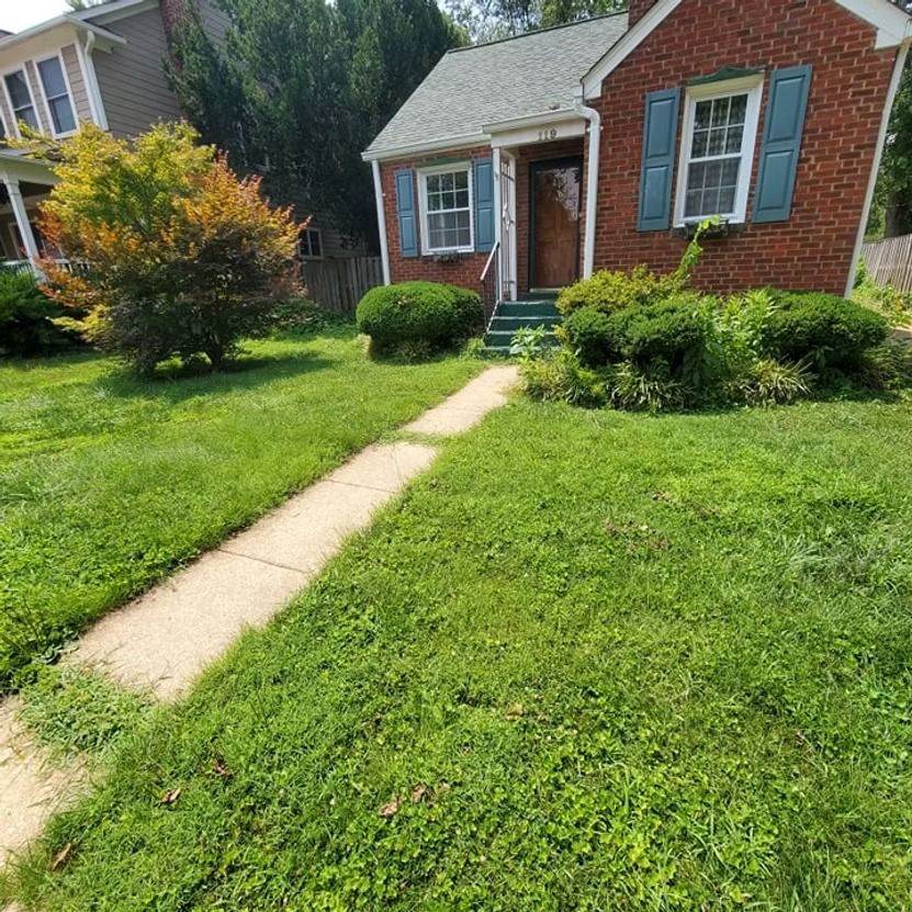 Brick house with blue shutters, front lawn, and a concrete walkway leading to the door