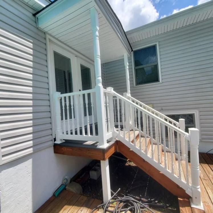 White house exterior with a small wooden accessibility ramp leading to a front porch entrance.