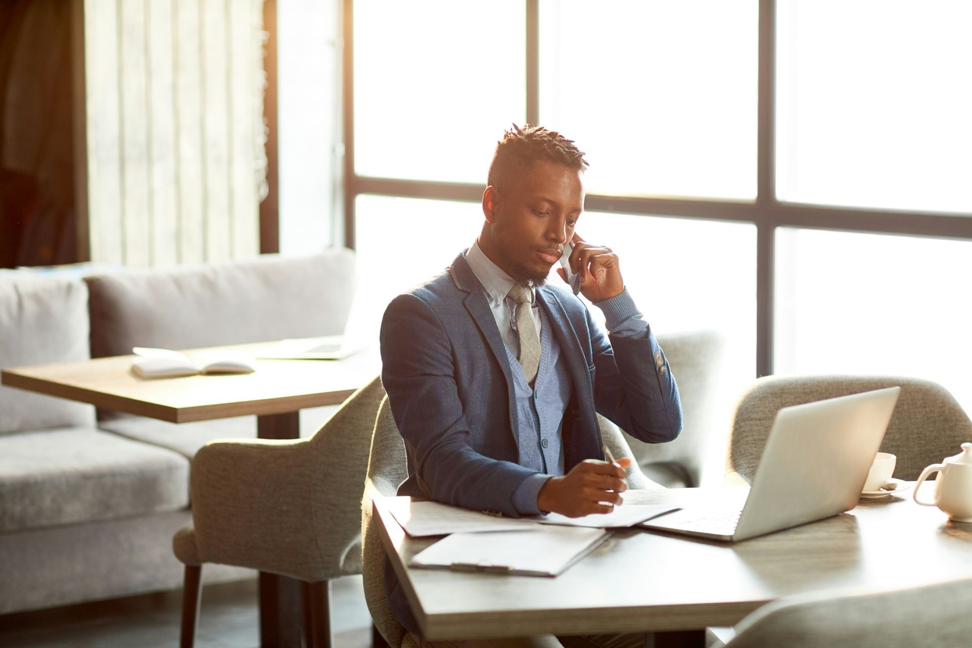 Person working on a laptop at a table in a bright office lounge