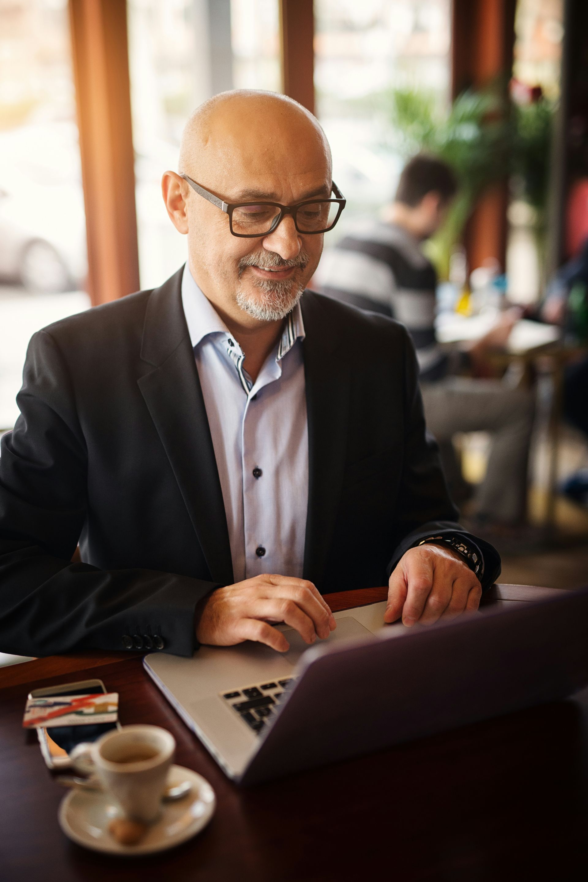 Man using a laptop at a café table with a cup of coffee