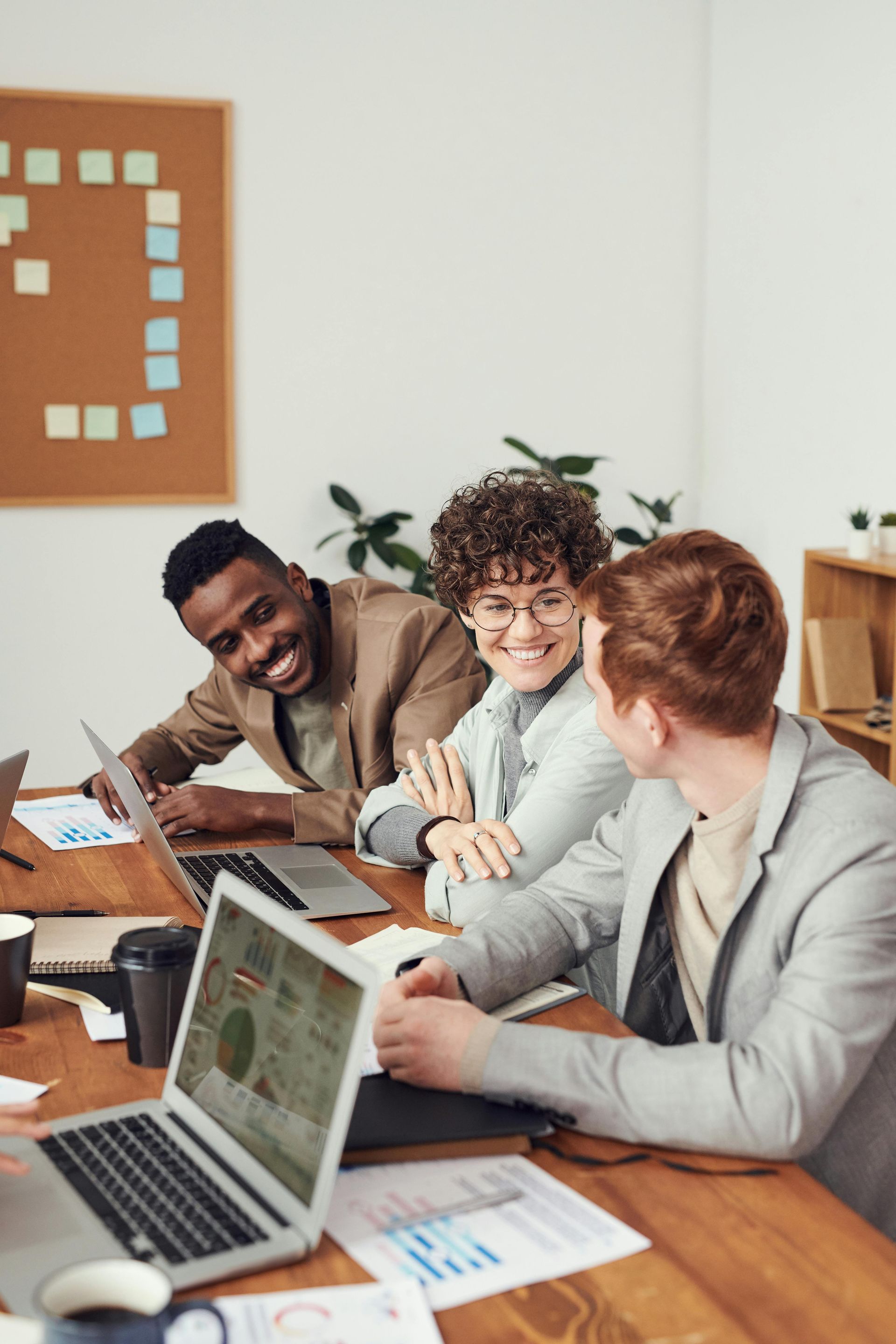 Three people working together at a laptop in a bright meeting room