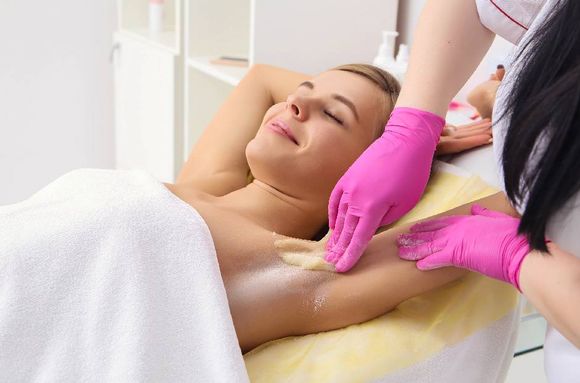 beautician removing hair of young woman
