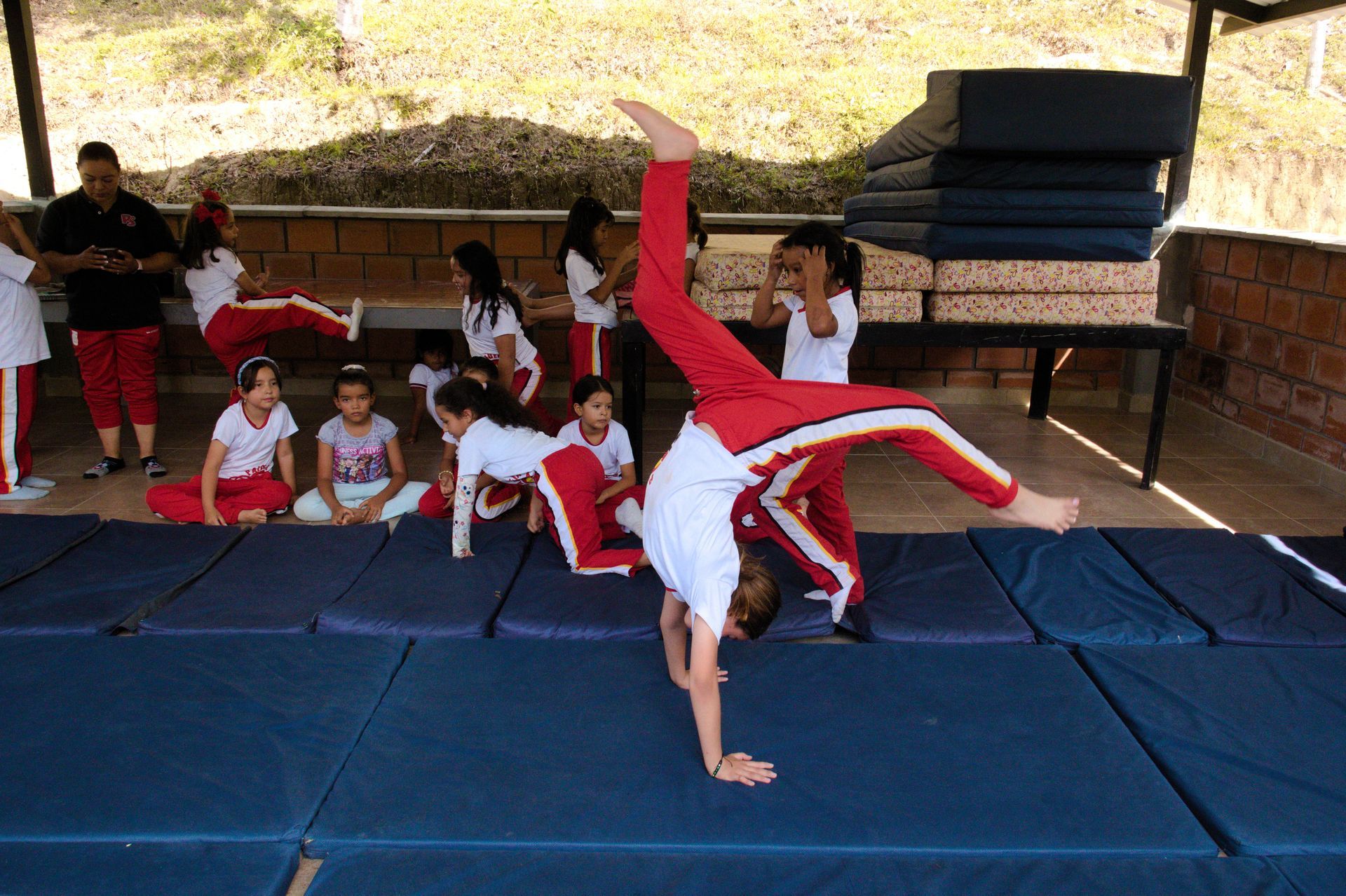 Un grupo de niños está haciendo el pino sobre una colchoneta.