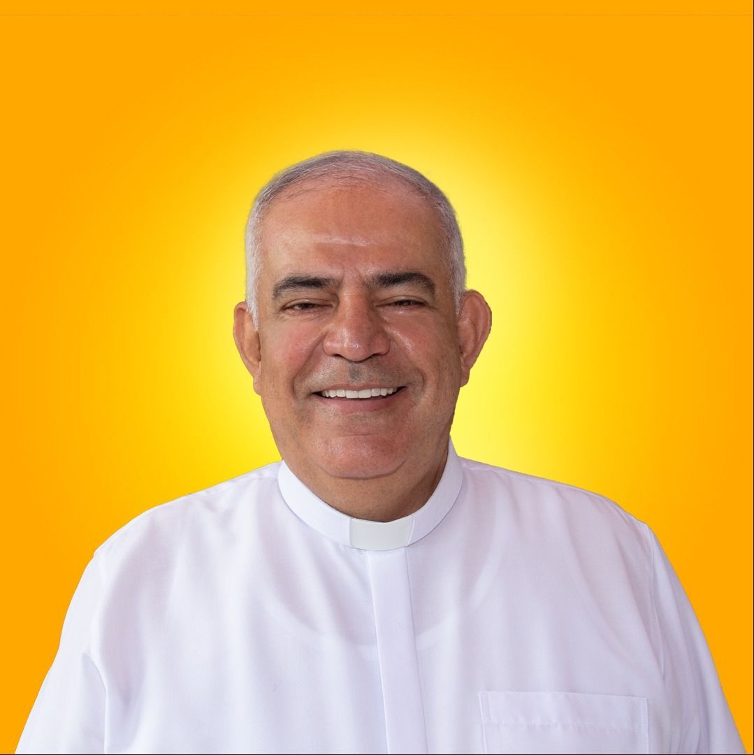 Un hombre con una camisa blanca sonríe frente a un fondo naranja
