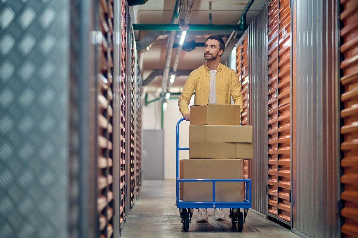 Worker pushing a cart of boxes through a warehouse aisle