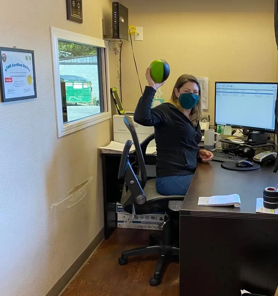 Woman wearing a face mask throws a green and black ball in an office. | Golden Gear Automotive