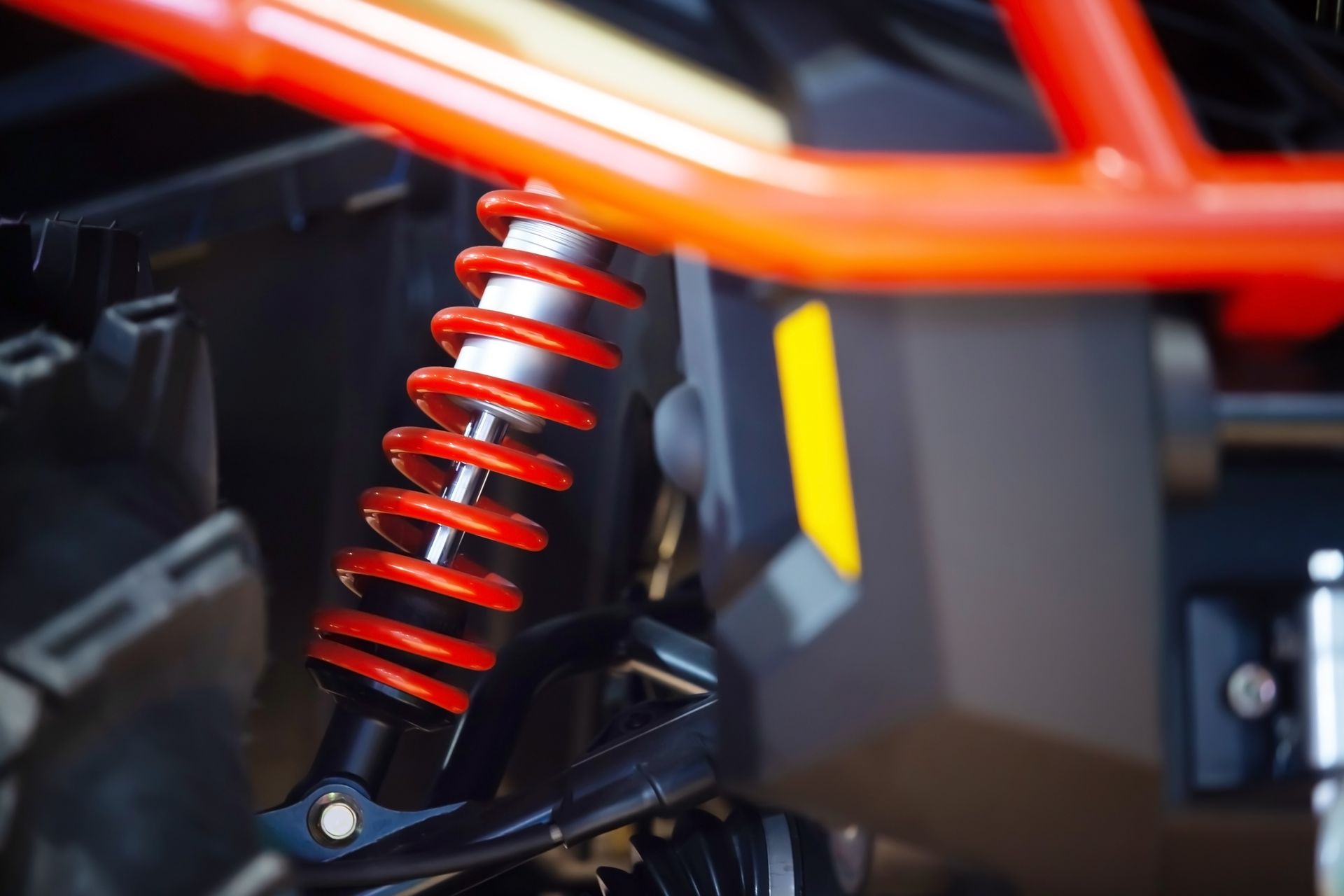 Red coil shock absorber on an ATV, with orange roll cage. | Golden Gear Automotive