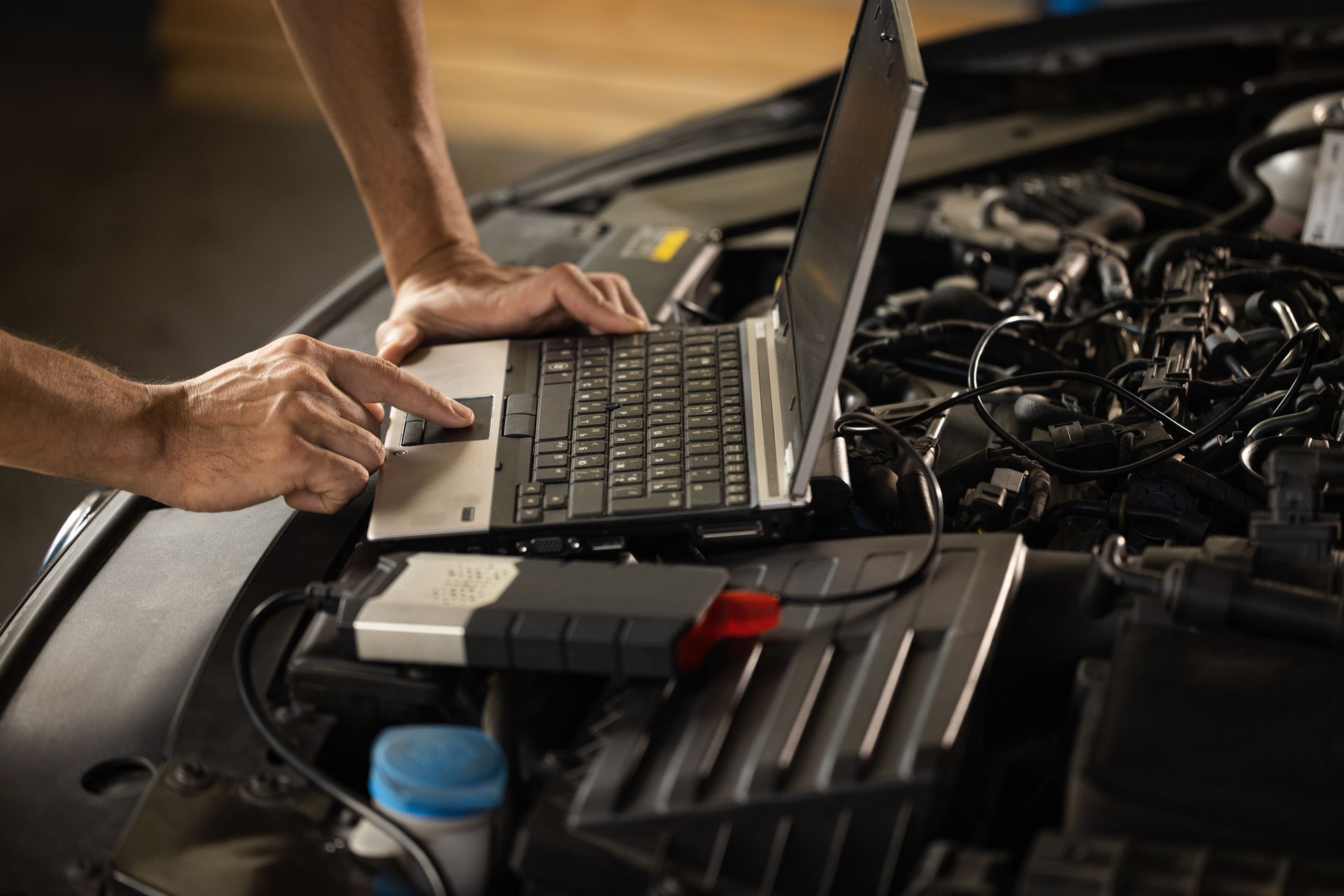 Mechanic using a laptop connected to a car engine for diagnostics. | Golden Gear Automotive