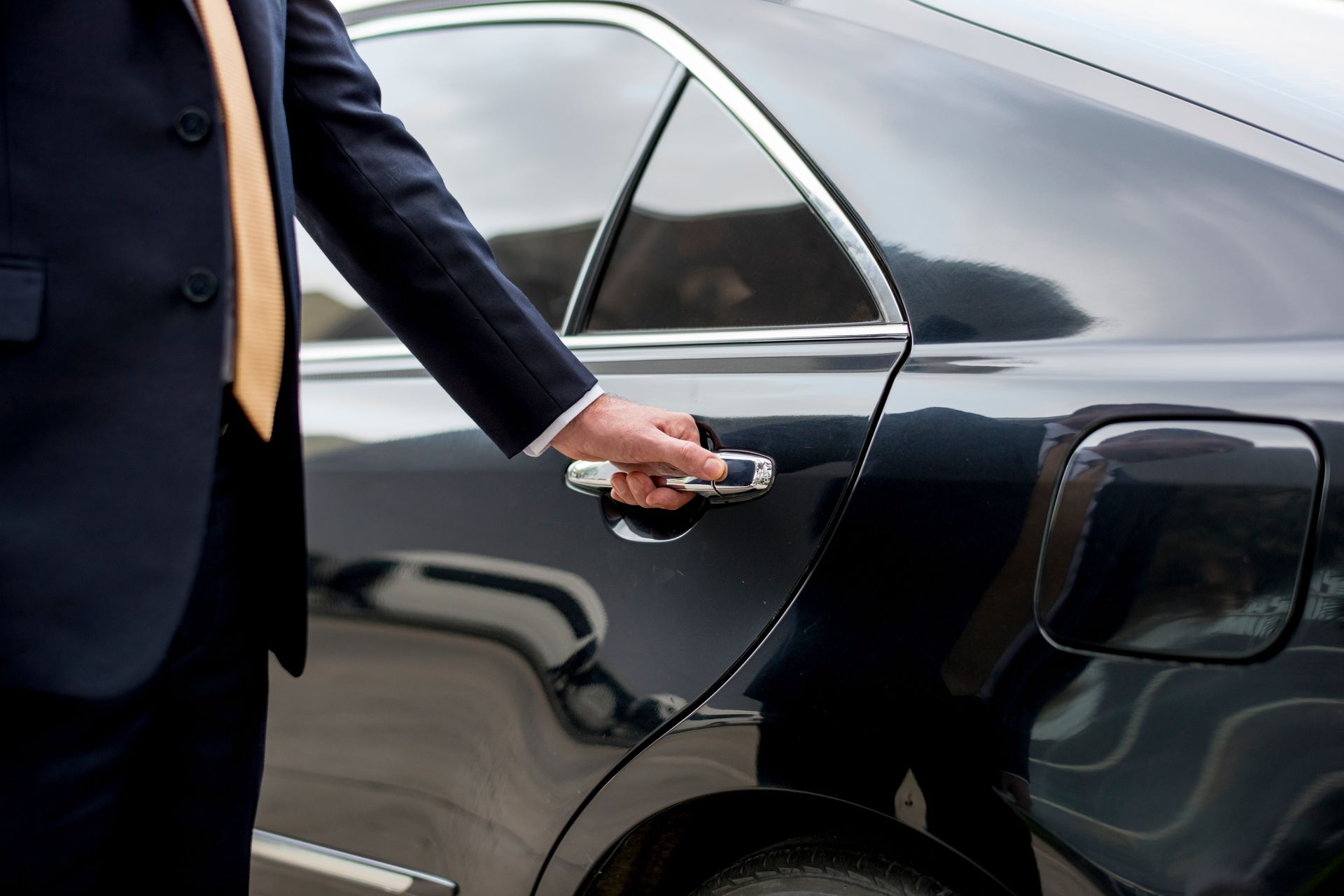 Someone opening the door to the back seat of a luxury transport limousine 