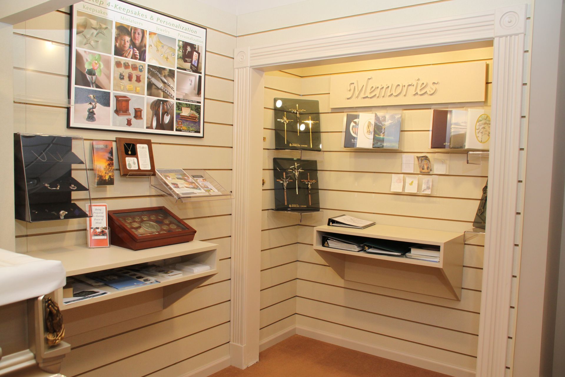 Small beige retail display nook with shelves, brochures, framed photos, and home decor items.