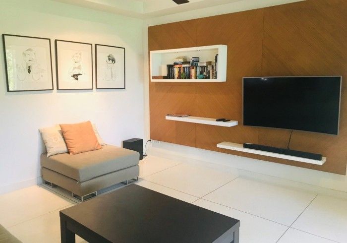 Living room with a floating TV, shelves, art, and a small sofa.