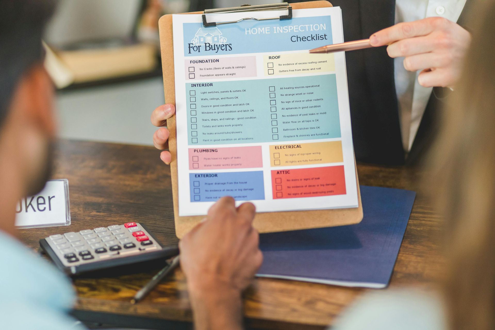 Person pointing at a checklist on a clipboard for a couple at a table.
