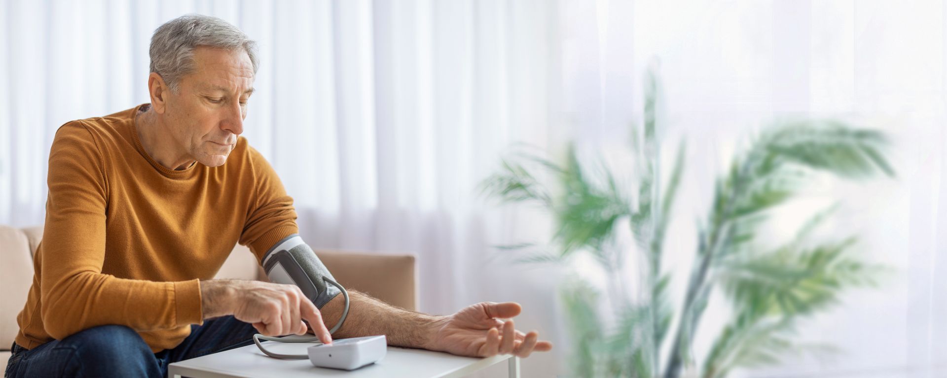 Man monitors blood pressure from the convenience of his home with remote patient monitoring. 