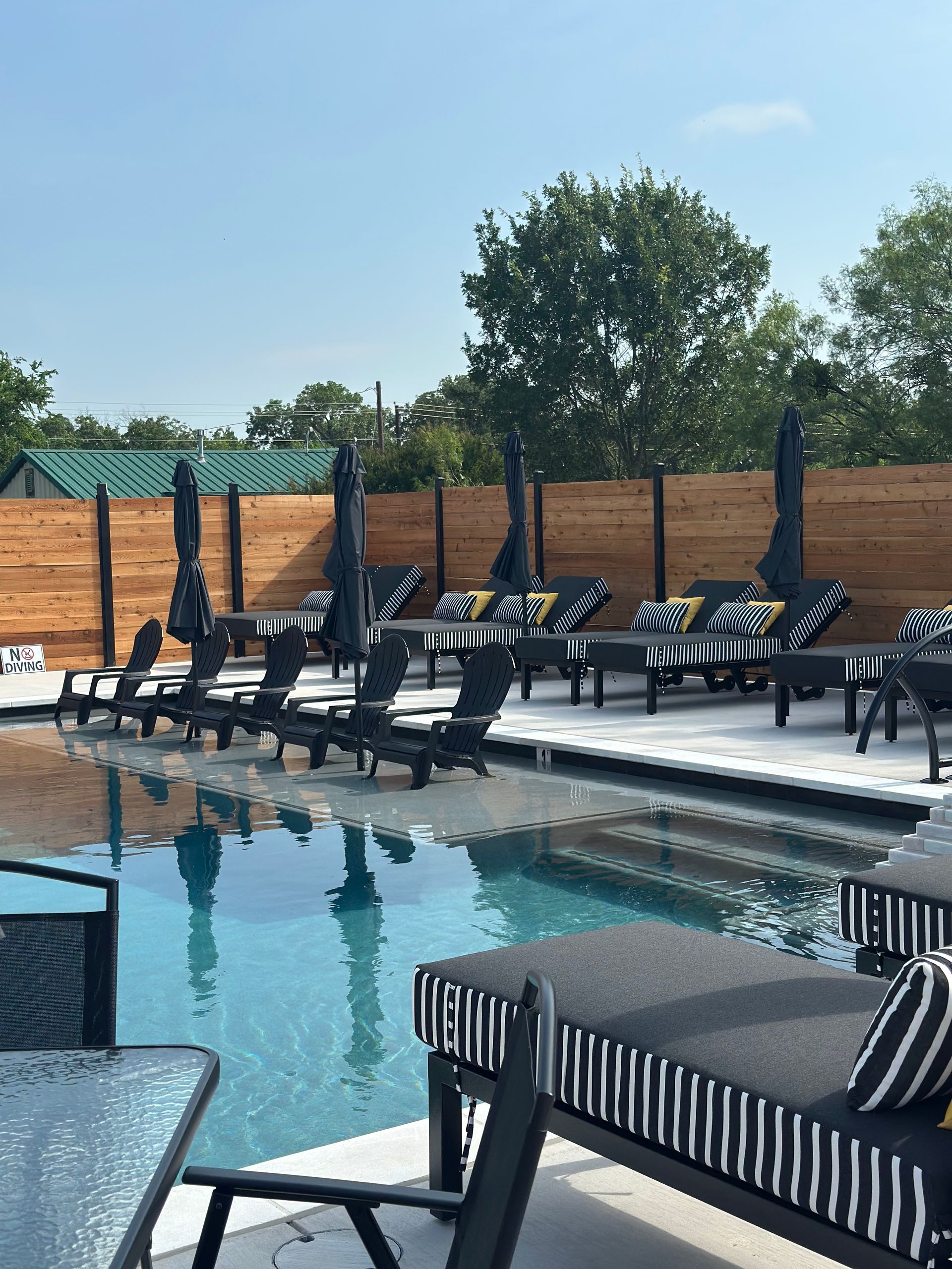Poolside lounge chairs beside a turquoise swimming pool under a clear sky