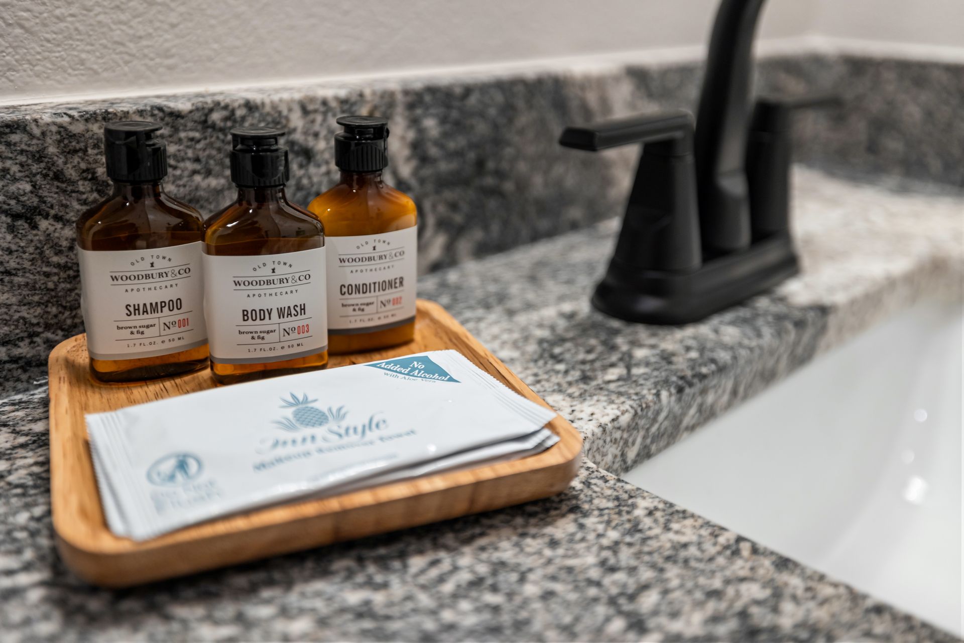Bath countertop with amber soap bottles, a soap bar, and a black faucet beside a sink