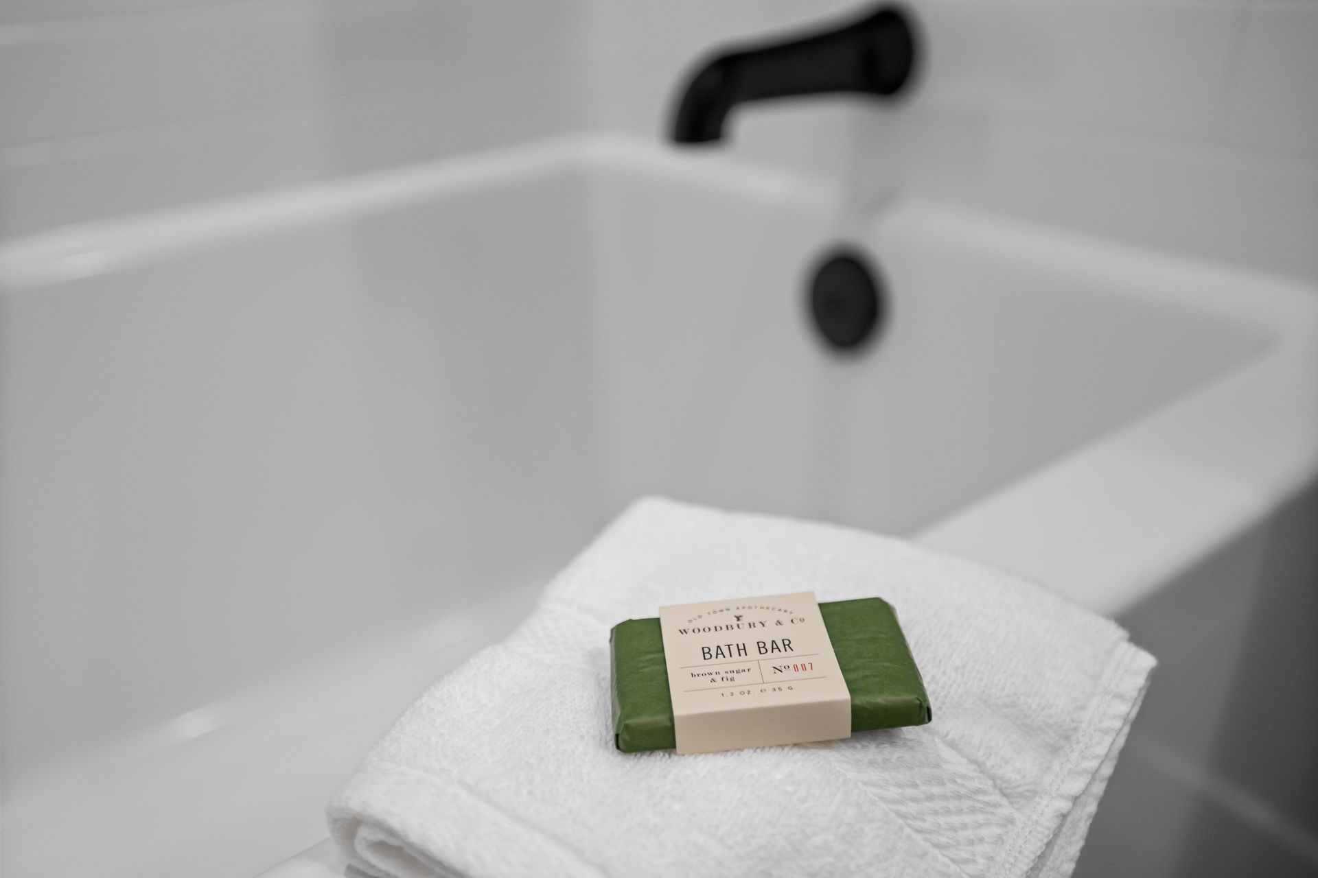 Soap bar on a white towel beside a bathtub faucet