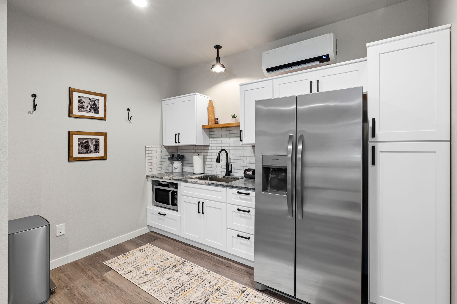 Modern white kitchen with stainless steel refrigerator, stove, sink, and cabinet storage