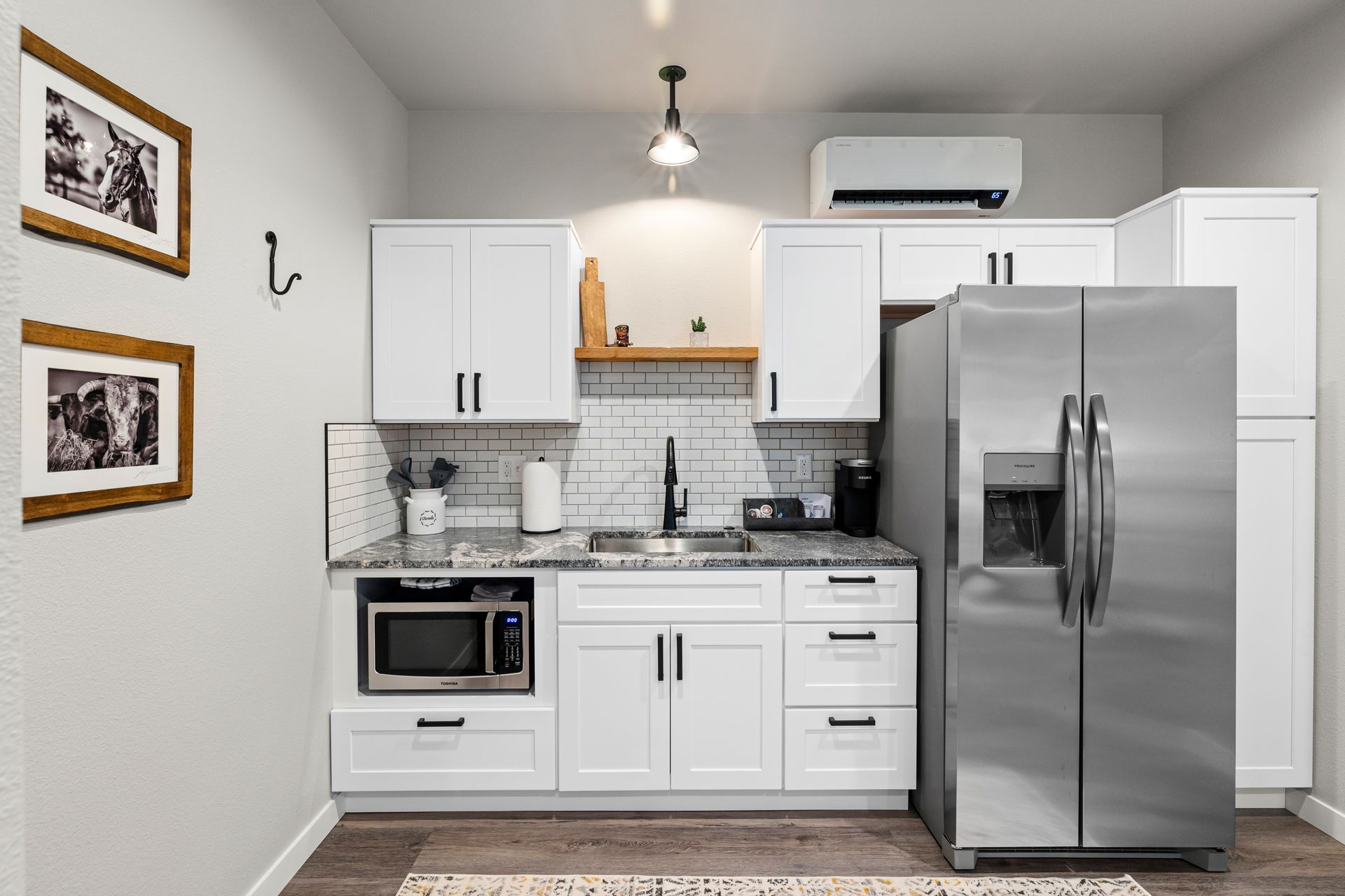 Modern white kitchen with stainless steel appliances, tiled backsplash, and a stainless fridge