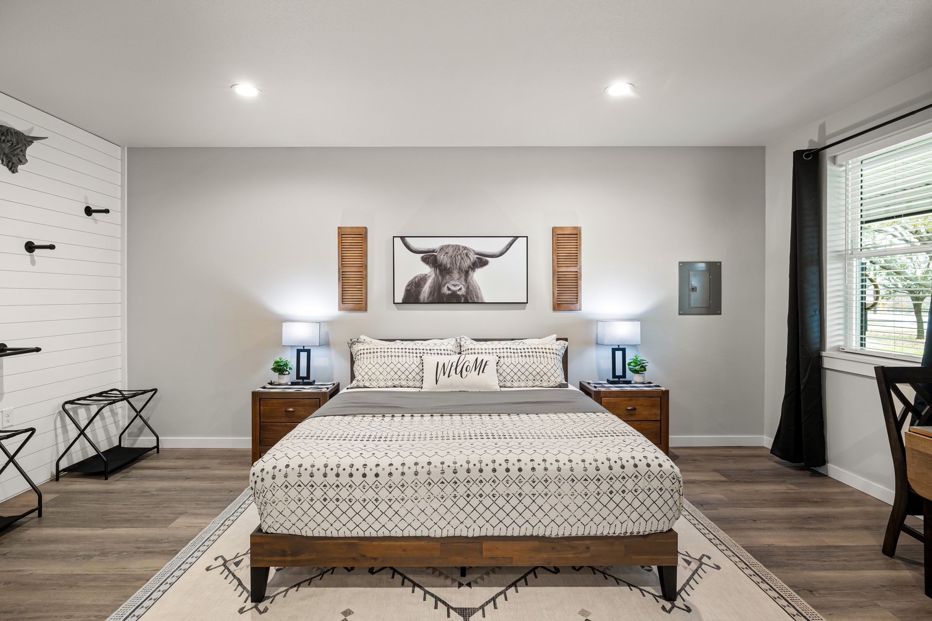Modern bedroom with a large bed, wooden nightstands, wall art, and recessed ceiling lights