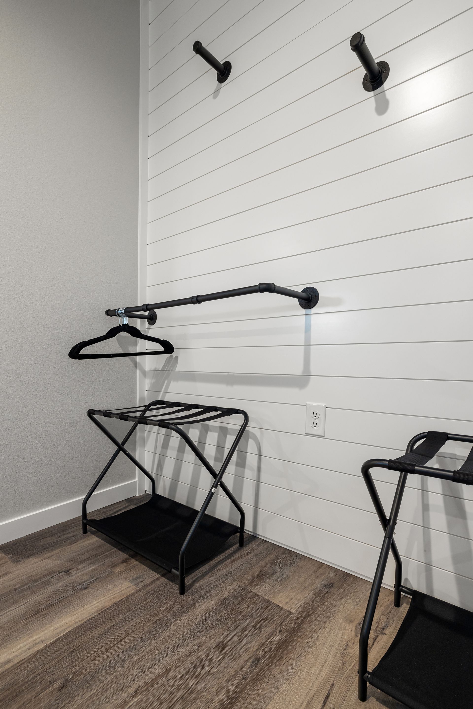 Retail store fitting area with wall hooks, a garment rod, and two folding display racks.