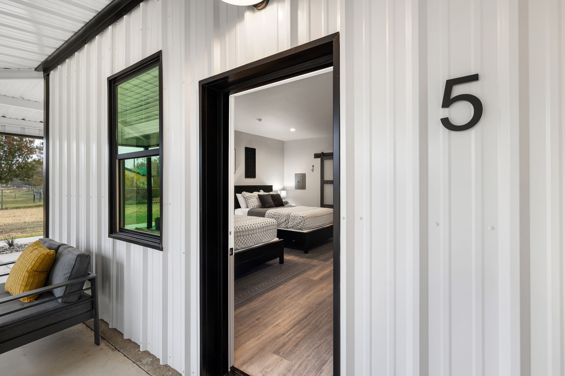 Black-and-white exterior of a modern tiny house, with open door and number 5 visible.