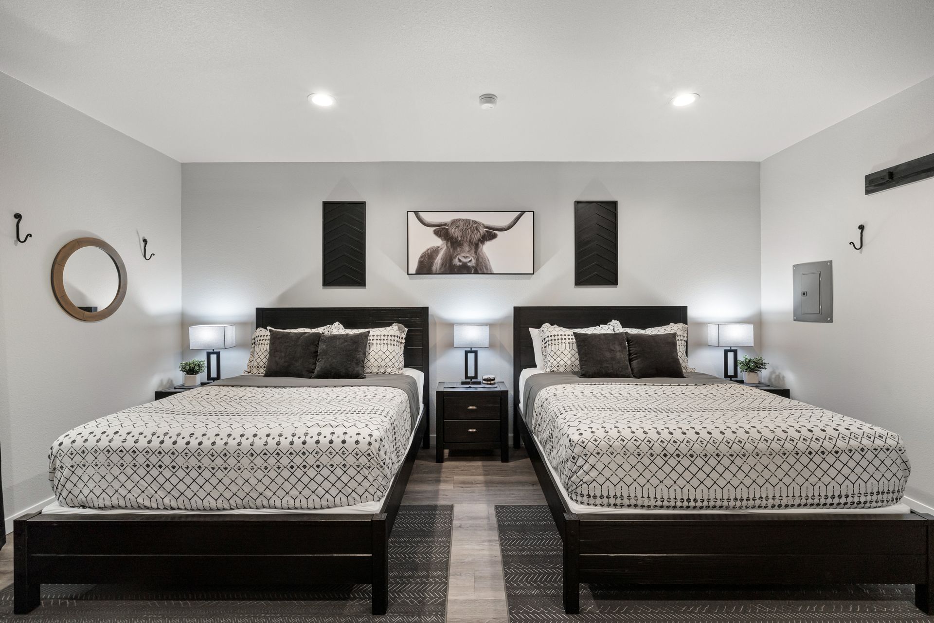 Modern bedroom with two black beds, gray walls, and a deer artwork above the headboards