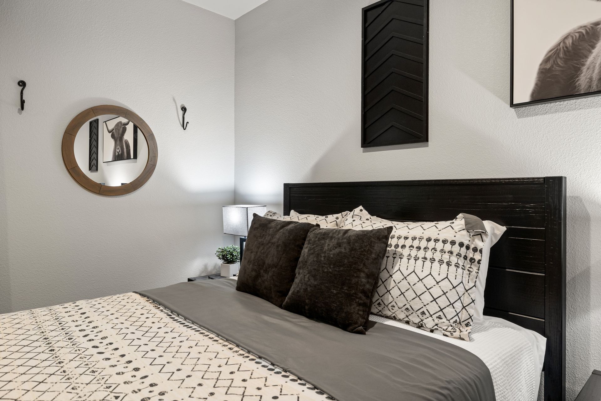 Modern bedroom with a black headboard, patterned bedding, and wall decor