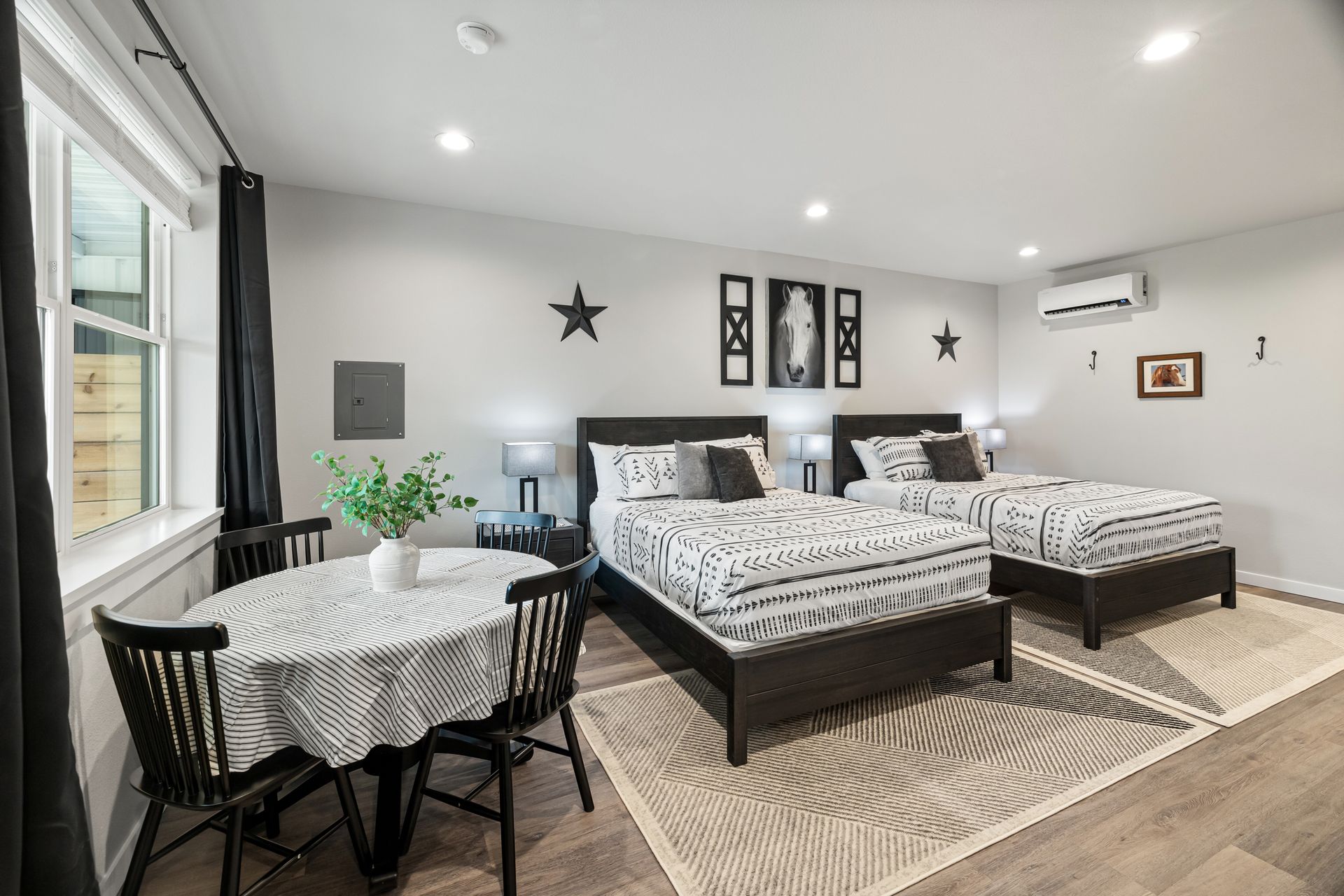 Bright bedroom with twin beds, striped bedding, a small table by the window, and wall star decor.