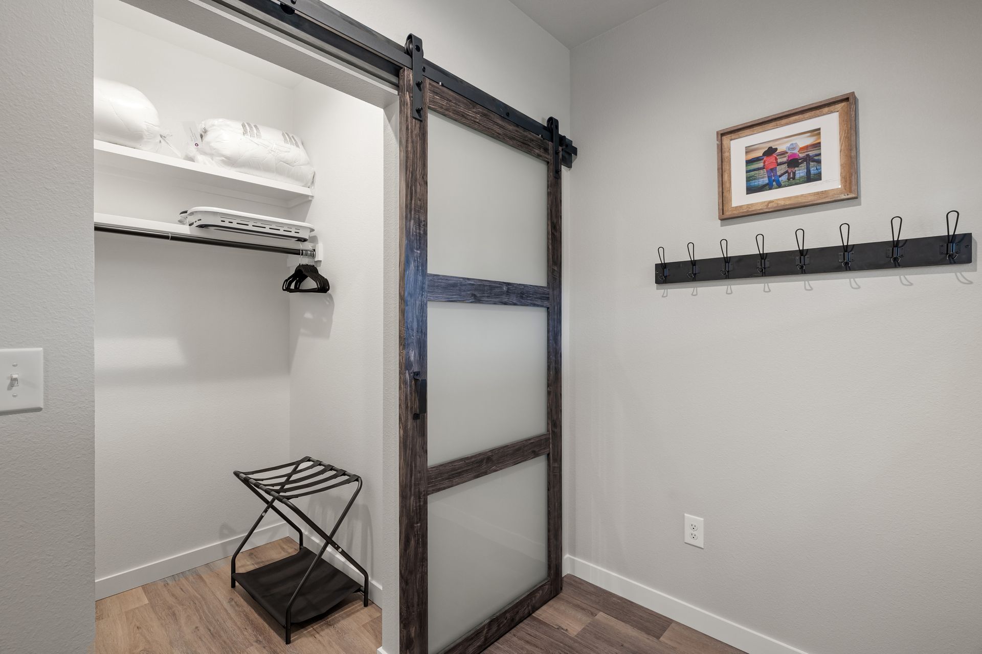 Minimal closet with barn door, shelving, hanging rod, and a small folded stool on the floor