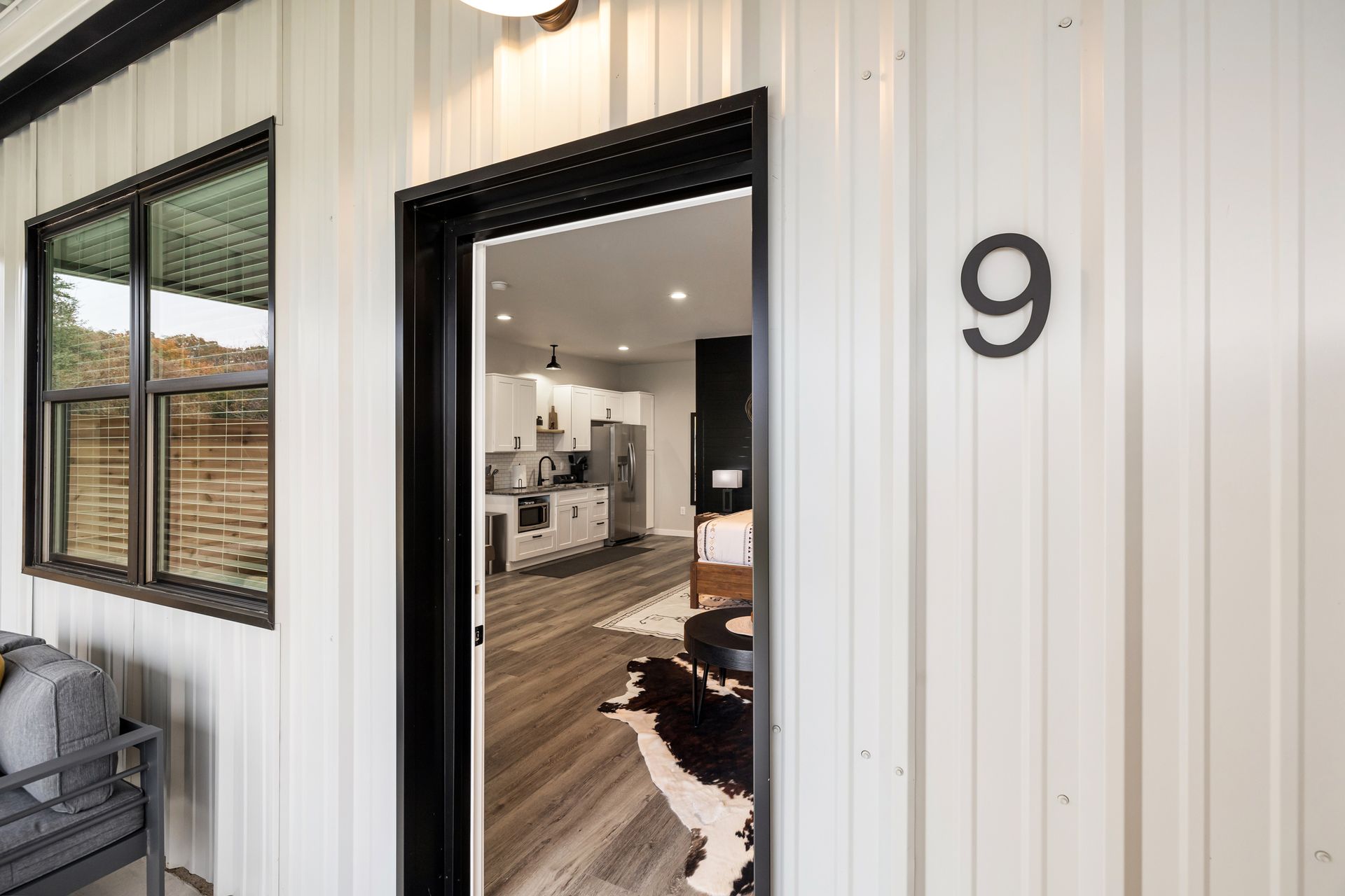 Exterior of a modern white house with black trim, open front door, and house number 9.