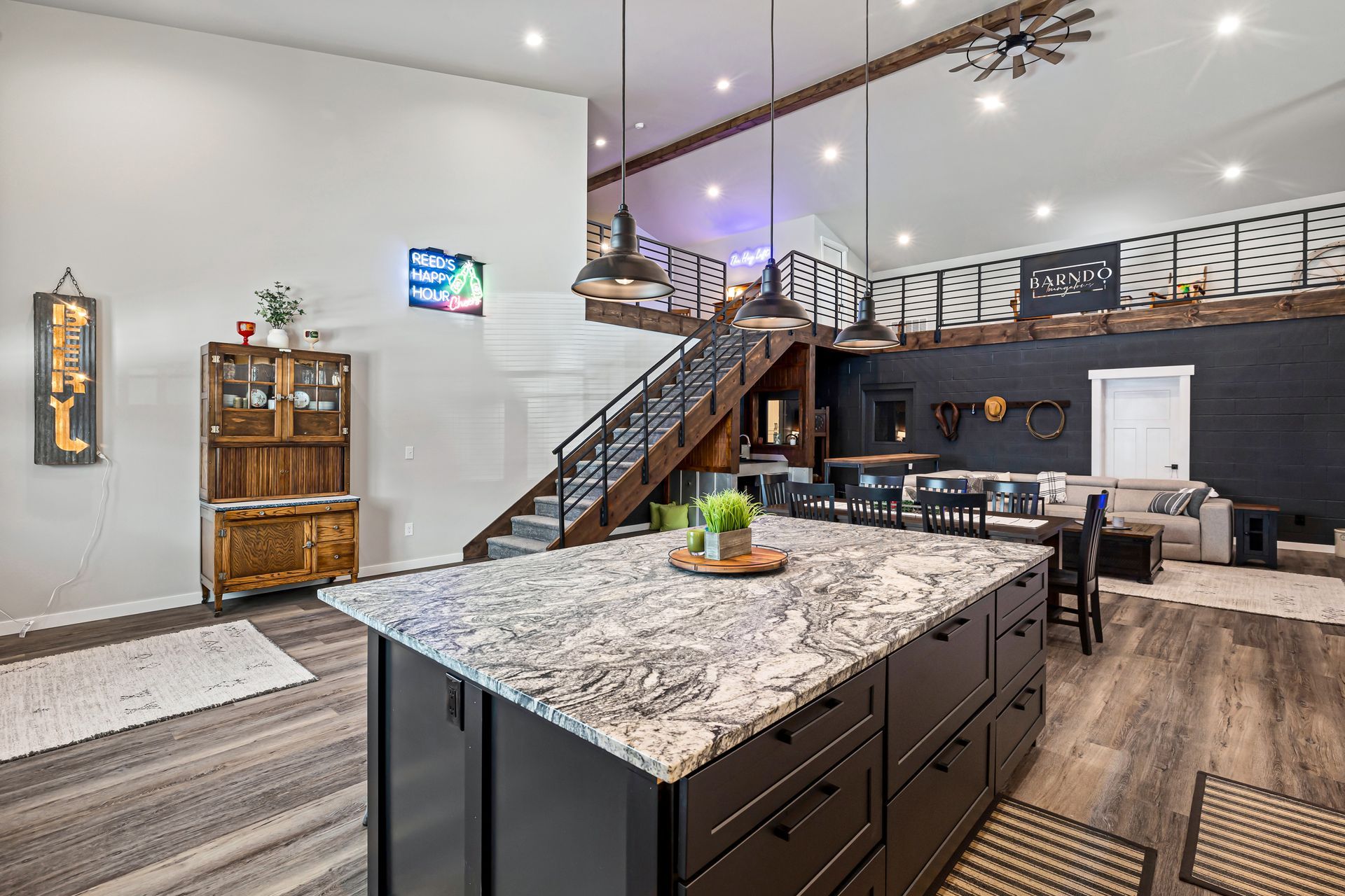 Modern open-concept kitchen and living room with granite island, staircase, and dark wood finishes