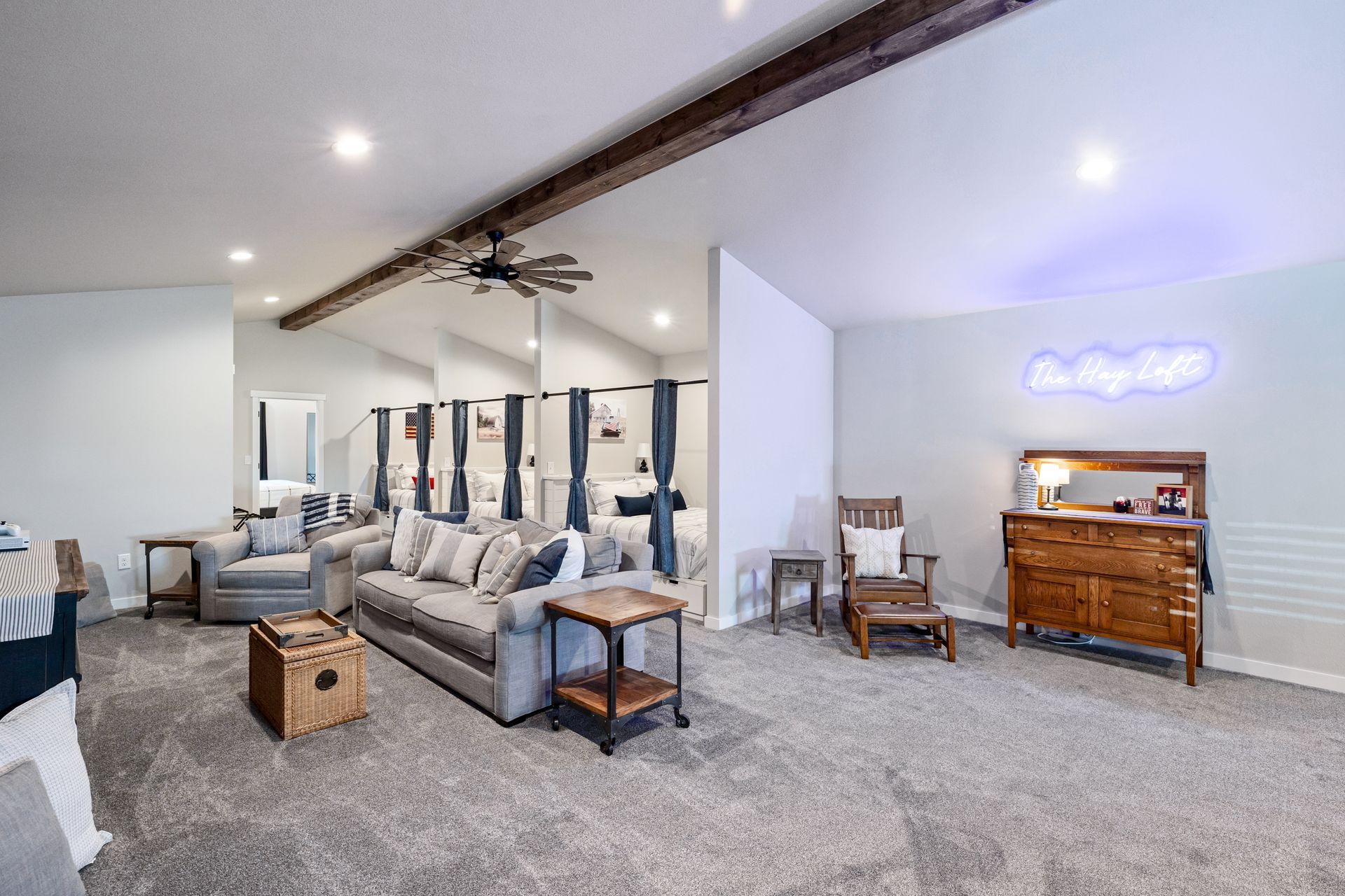 Spacious gray-carpeted living room with sectional sofa, armchairs, piano, and mirrored wall accents.