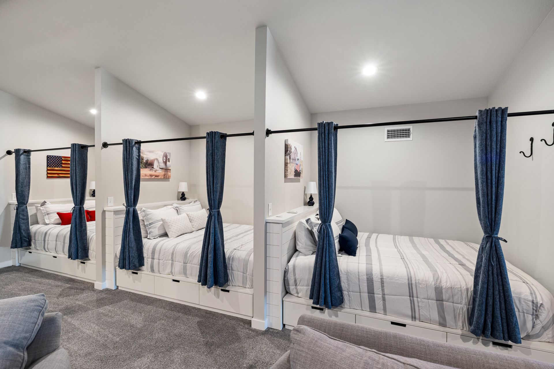 Bright bunk bed room with white walls, blue curtains, and gray carpet in a dorm-like space