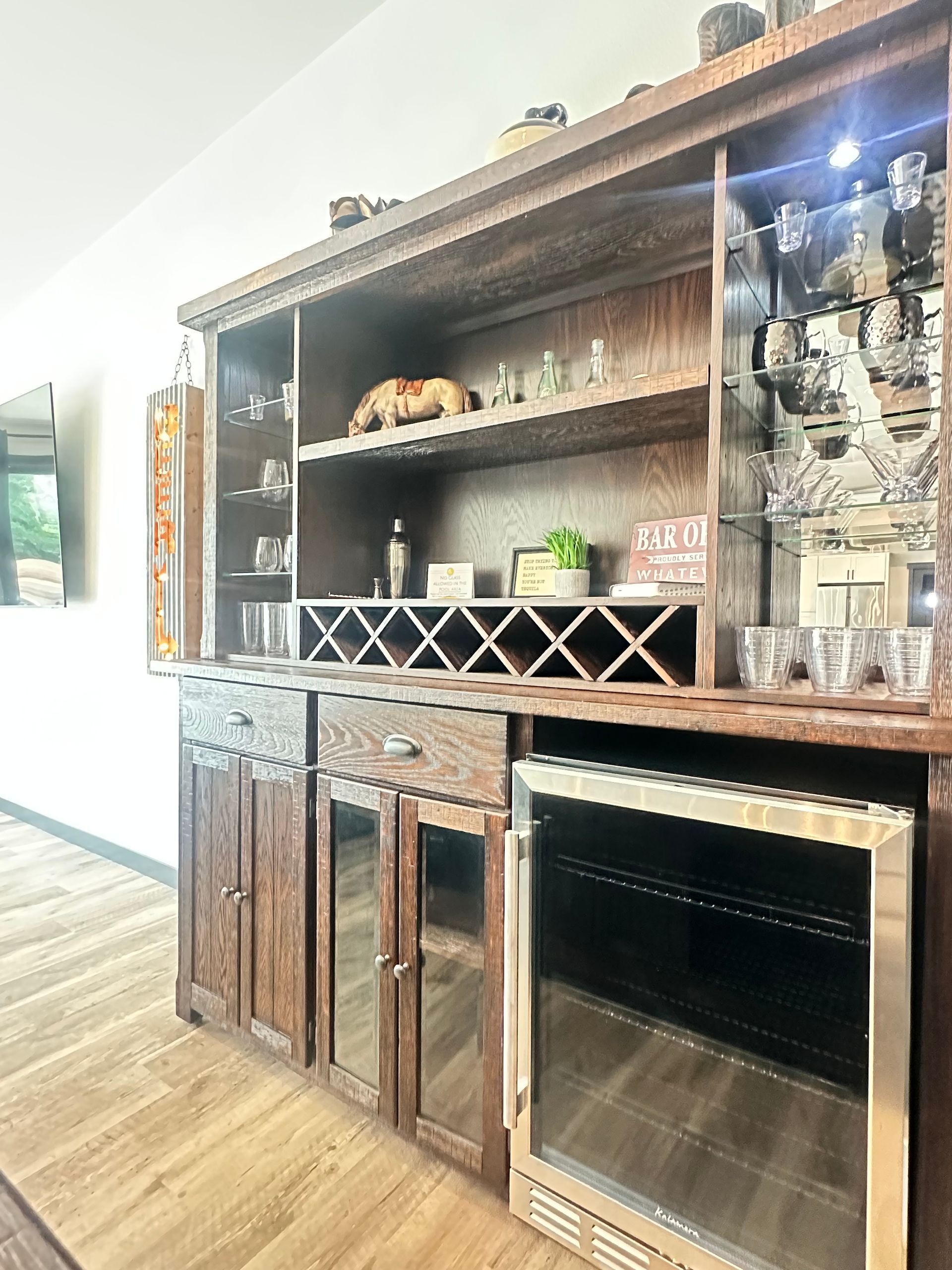Wooden built-in cabinet with open shelves, decor, and a stainless fireplace in a bright room.