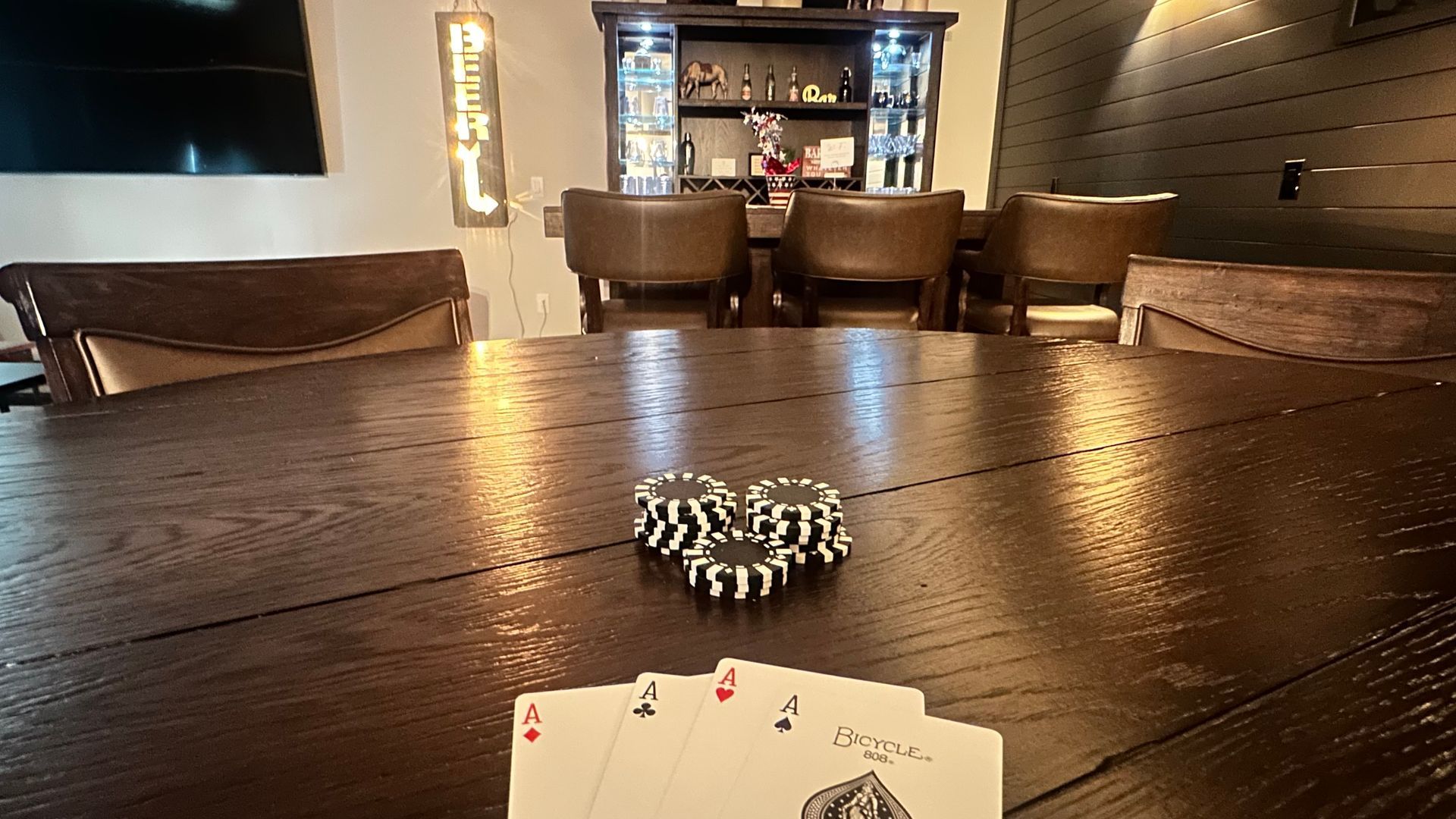 Poker chips and cards on a wooden table in a dimly lit bar or lounge.
