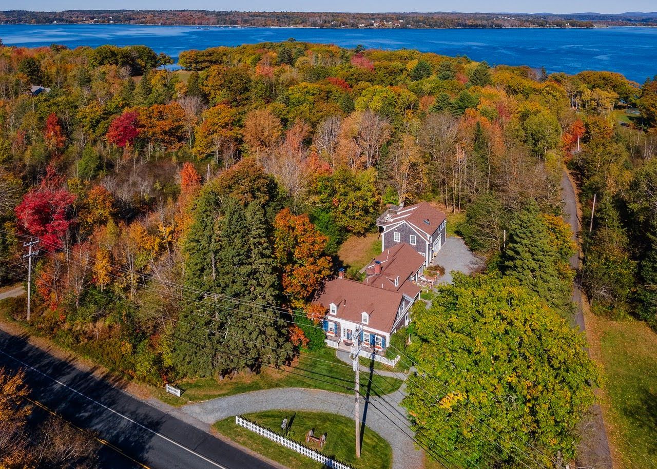 Aerial view of Coach Stop Inn building and property amid autumn trees and the Eastern Bay.
