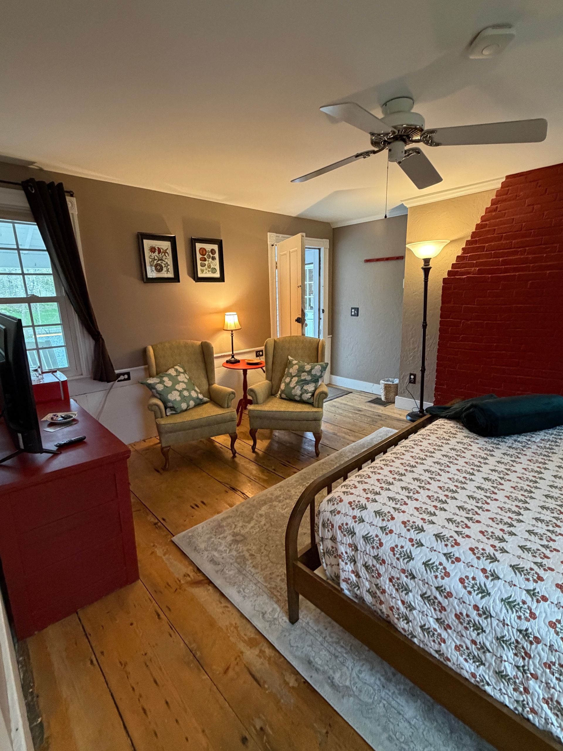 Bedroom with a bed, chair, lamp, rug, and wooden floors.